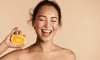 Woman with Shiny Skin Holding Orange